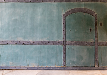 Closed wooden blue door in a wooden blue wall and tiled marble floor