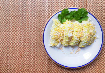 Thai traditional dessert, Thai sweet dessert, mung bean rice-crepe and coconut,white sesame in white plate on wooden table background.
