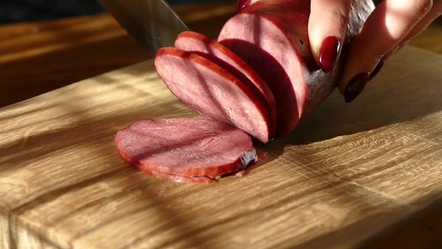 Slicing sausage on a cutting board. Beef sausage. Cut with a kitchen knife.