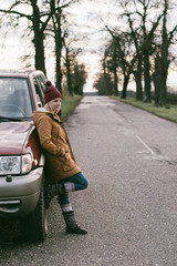 Fototapeta premium Woman waiting by a car. Off road vehicle and girl on the road.