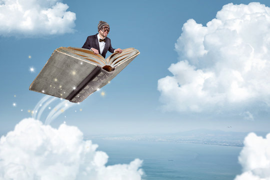 Mann fliegt auf einem Buch über die Wolken