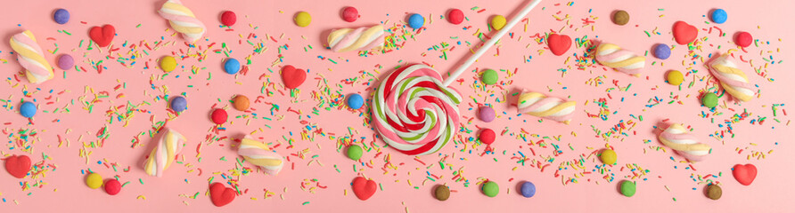 Colorful candies on pink background, top view