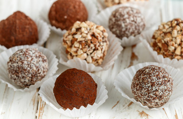 Assorted dark chocolate truffles with cocoa powder, coconut and chopped almonds closeup. Homemade candy. Selective focus