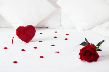Valentines day surprise at morning on the white bed for her. Red heart background with rose with box. copy space