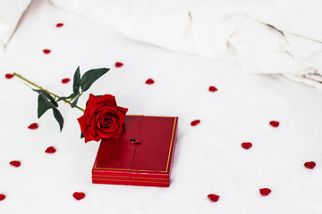 Valentines day surprise at morning on the white bed for her. Red heart background with rose with box. copy space
