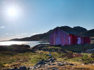 Red boat house at pier, rocky island, Norway. Traditional red white building at pier close to sea