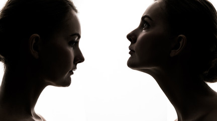 Silhouette of face to face women.