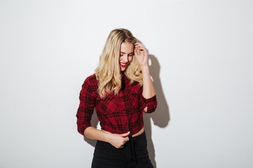 Cheerful young blonde woman standing isolated