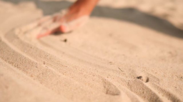 Female Hand Drawing Calm Lines on White Sand at Tropical Island Beach in Thailand. 4K, Slowmotion.