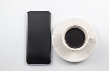 Cup of coffee and smartphone on white background, Modern workspace with  coffee cup and smartphone copy space on white background. Top view.