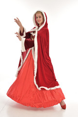 full length portrait of pretty blonde lady wearing red and white christmas inspired costume gown, standing pose on white background.