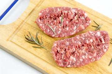 Fresh pork sausages isolated on white background, -raw sausage for cooking on cutting board with rosemary on a white background, top view