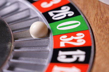 Macro shot of a roulette in a casino where the ball goes to the green or red or black number. People having bet and bet money may have won lost badges. Concept of: fate, gambling, luck, destiny.