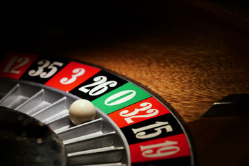 Macro shot of a roulette in a casino where the ball goes to the green or red or black number. People having bet and bet money may have won lost badges. Concept of: fate, gambling, luck, destiny.