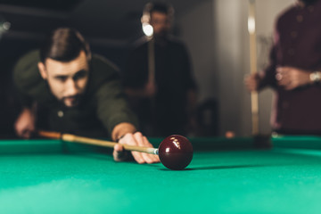 young successful handsome man playing in russian pool at bar with friends