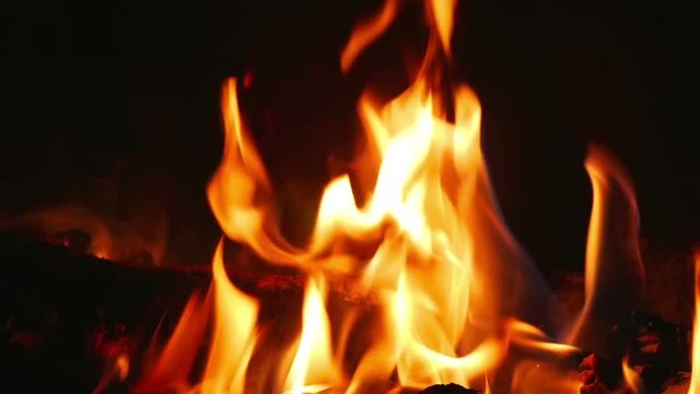 Orange flames from burning logs in indor open fireplace in super slow motion.