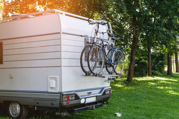 White trailer attached to a Bicycle stands on a clearing in the woods on a Sunny day.