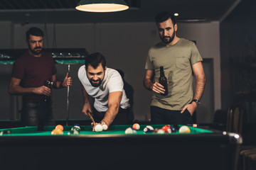 group of young successful handsome men playing in pool at bar