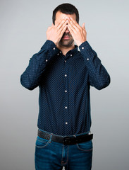 Handsome man covering his eyes on grey background