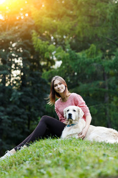 Image from below of woman sitting with dog on green lawn