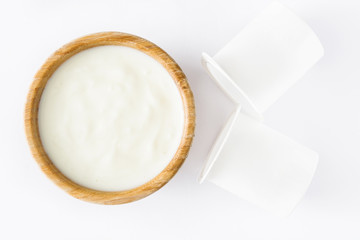 Natural yogurt in wooden bowl isolated on white background. Top view