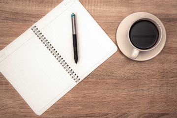 A cup of coffee with note and pen on working table with copy space top view.