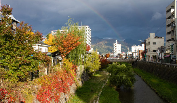 The colorful foliage at the riverside with rainblow and dark cloud.