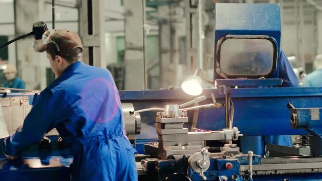 Industrial worker using modern turning lathe for metalworking details back view