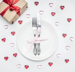 Fototapeta na wymiar composition for Valentine's day knife and fork tied with ribbon on a plate with decorative hearts