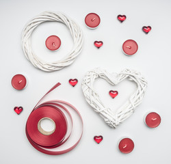 composition for Valentine's Day, red aromatic candles, packing tape, rattan wreaths in the shape of heart, top view
