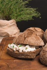 Homemade farm bread with cottage cheese curd and thyme herb, malt flour and curd cream in bowl on wooden table
