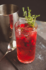 Christmas cocktail with berries and thyme on the rustic background. Selective focus.