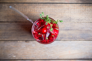 Christmas cocktail with berries and thyme on the rustic background. Selective focus.