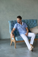 Sexy man model siting on the aqua vintage sofa and looking away
