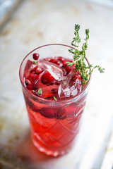 Christmas cocktail with berries and thyme on the rustic background. Selective focus.