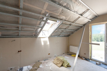 Attic room under construction with gypsum plaster boards and windows