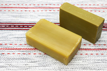 Two pieces of the natural handmade organic olive oil soap on the wooden table. Rustic background. Bath spa accessories. Table doily with the soap.