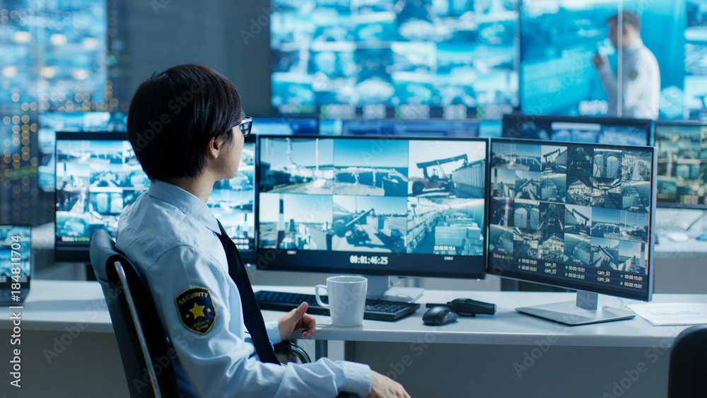 Poster in the security control room officer monitors multiple screens for suspicious activities, he drinks 
