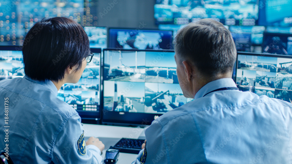 Poster In the Security Control Room Two Officers Monitoring Multiple Screens for Suspicious Activities, They Report any Unauthorised Activities with Walkie-Talkie. They  Guard Object of National Importance.