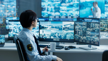 In the Security Control Room Officer Monitors Multiple Screens for Suspicious Activities, He Drinks...