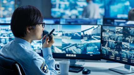 In the Security Control Room Officer Monitors Multiple Screens for Suspicious Activities, He...