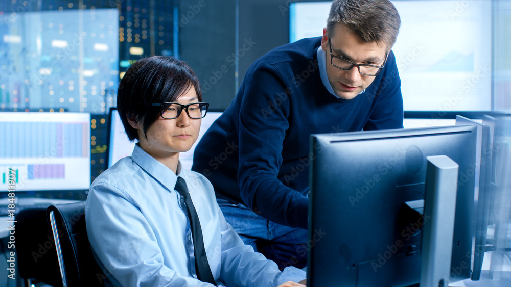Poster In the Data Mining Center Chief Statistician Consults His Young Assistant sits at His Workstation Surrounded with Monitors Displaying Data and Graphs.