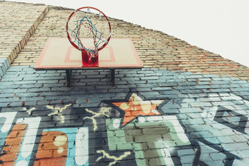 Fototapeta na wymiar bottom view of basketball hoop on wall with colorful graffiti