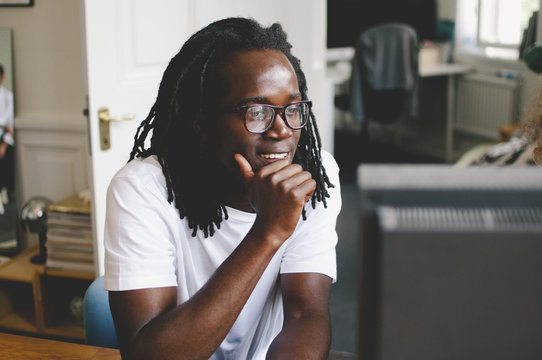 Young businessman with hand on chin looking at computer in creative office