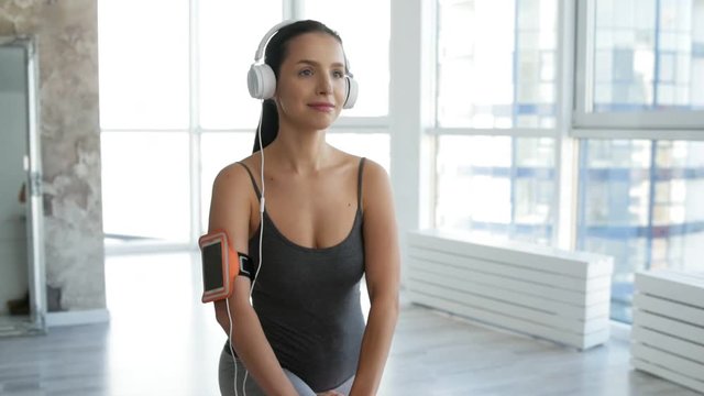 Caring about beauty. Close up of positive young woman doing exercises while listening to music and expressing positive emotions