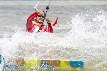 Dad and son are kitesurfing on the sea. The son clings to Papa's back