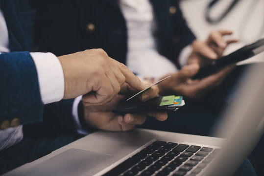 Cropped image of senior man holding credit card while doing online shopping in yacht