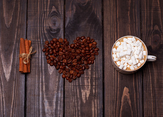Heart shape made from coffee beans with a cinnamon and cup of coffee on hessian spelling I love coffee