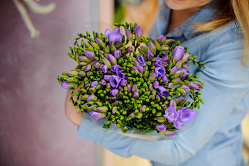 Woman holding a beautiful flower bouquet in purple and green tones for Valentine's day