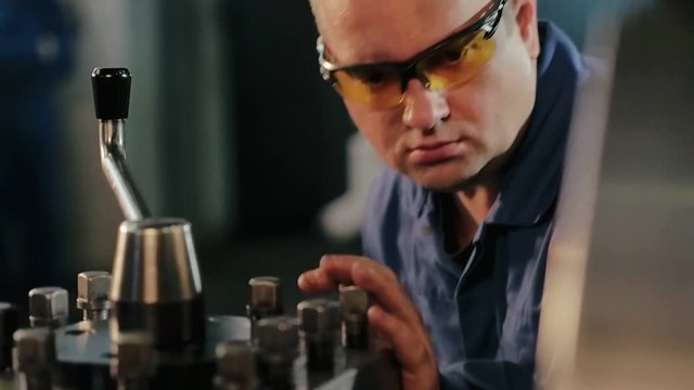 Industrial employee in protective eyewear working on metalworking machine
